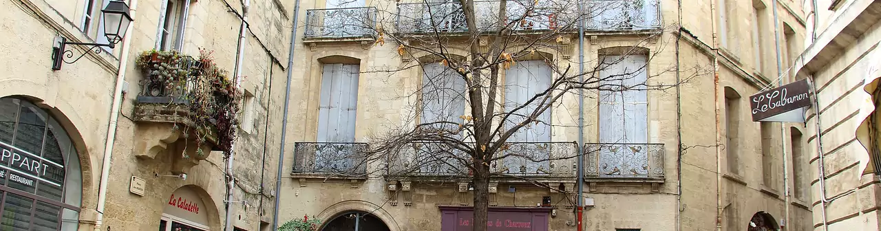 Une place de l'Écusson, le centre historique de Montpellier : façades en pierre et balcons en fer forgé